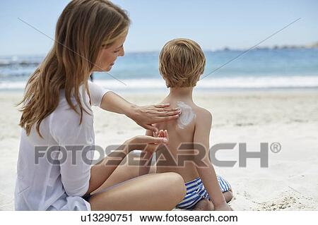 Stock Image - Mother applying sun cream to son. Fotosearch