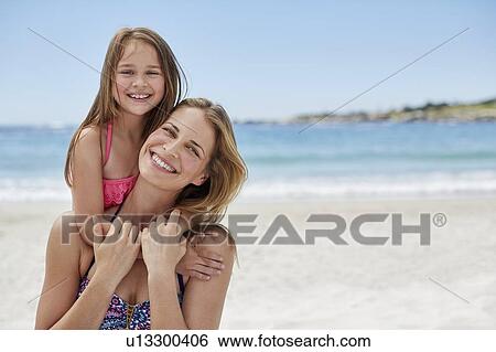 Stock Photograph - Mother carrying daughter on back. Fotosearch
