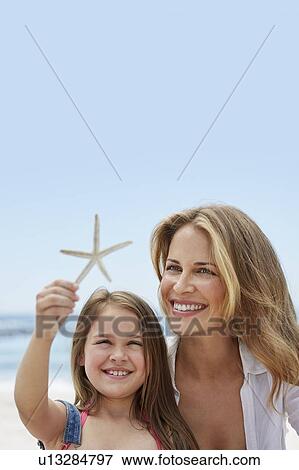 Stock Photo - Mother with daughter holding a starfish. Fotosearch