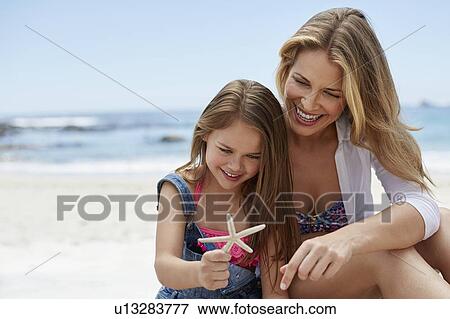 Stock Photo - Mother with daughter holding starfish. Fotosearch