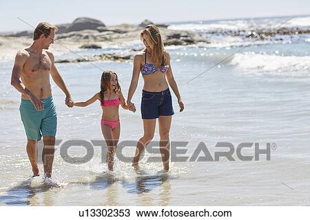 Parents walking on beach with daughter View Large Photo Image Stock Image - Parents walking on beach with daughter. Fotosearch