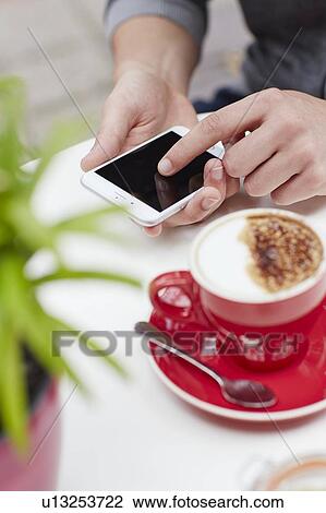 Stock Image - Person using smartphone with coffee. Fotosearch