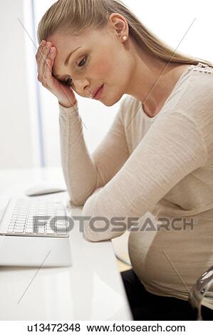 Pregnant woman at desk with head in hands View Large Photo Image Stock Photo - Pregnant woman at desk with head in hands. Fotosearch