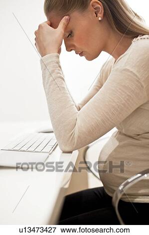 Pregnant woman at desk with head in hands View Large Photo Image Stock Photo - Pregnant woman at desk with head in hands. Fotosearch