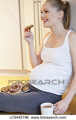 Pregnant woman eating biscuit View Large Photo Image Stock Photograph - Pregnant woman eating biscuit. Fotosearch