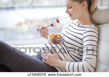 Pregnant woman eating fruit salad View Large Photo Image Stock Photo - Pregnant woman eating fruit salad. Fotosearch