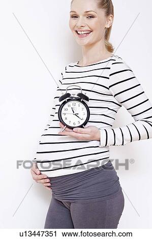 Pregnant woman holding alarm clock View Large Photo Image Stock Image - Pregnant woman holding alarm clock. Fotosearch