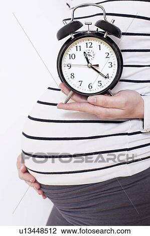 Pregnant woman holding alarm clock View Large Photo Image Stock Image - Pregnant woman holding alarm clock. Fotosearch
