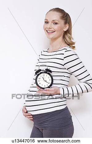 Pregnant woman holding alarm clock View Large Photo Image Stock Photograph - Pregnant woman holding alarm clock. Fotosearch