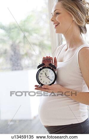 Pregnant woman holding alarm clock View Large Photo Image Stock Photography - Pregnant woman holding alarm clock. Fotosearch