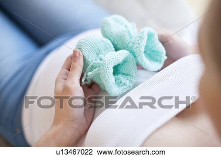 Stock Image - Pregnant woman holding baby booties. Fotosearch