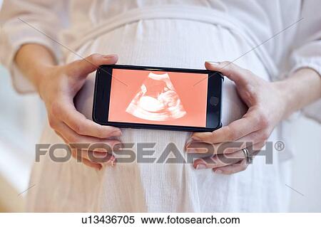 Stock Photography - Pregnant woman holding baby scan. Fotosearch