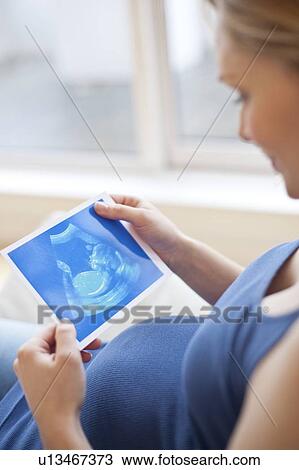 Stock Image - Pregnant woman looking at baby scan. Fotosearch
