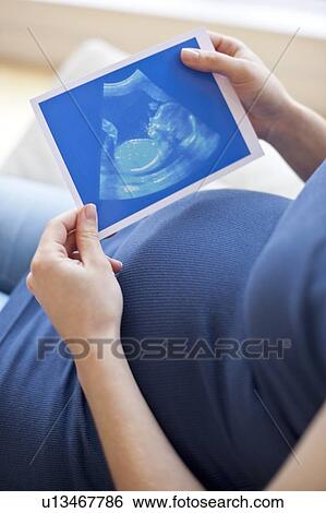 Stock Photograph - Pregnant woman looking at baby scan. Fotosearch