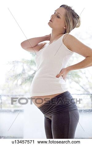 Stock Image - Pregnant woman rubbing her neck. Fotosearch