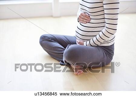 Stock Photography - Pregnant woman sitting on the floor. Fotosearch