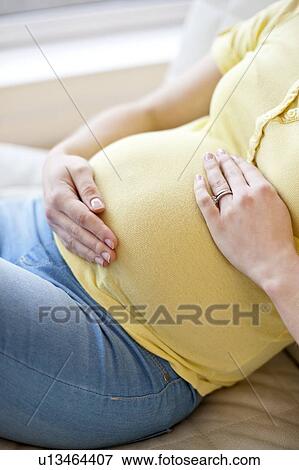 Stock Photo - Pregnant woman touching tummy. Fotosearch