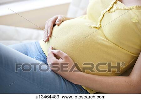 Stock Photo - Pregnant woman touching tummy. Fotosearch