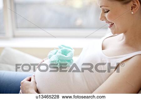 Stock Photo - Pregnant woman with baby booties on tummy. Fotosearch