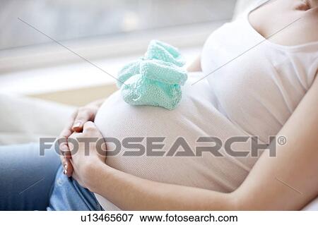 Pregnant woman with baby booties on tummy View Large Photo Image Stock Photo - Pregnant woman with baby booties on tummy. Fotosearch