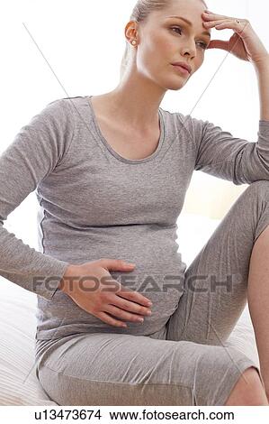 Pregnant woman with hand on head View Large Photo Image Picture - Pregnant woman with hand on head. Fotosearch