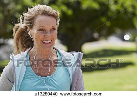 Stock Image - Senior woman wearing earphones. Fotosearch