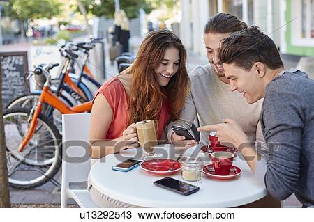 Stock Image - Three young friends with smartphone. Fotosearch