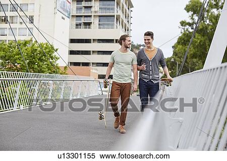 Two young men walking with skateboards View Large Photo Image Stock Photography - Two young men walking with skateboards. Fotosearch