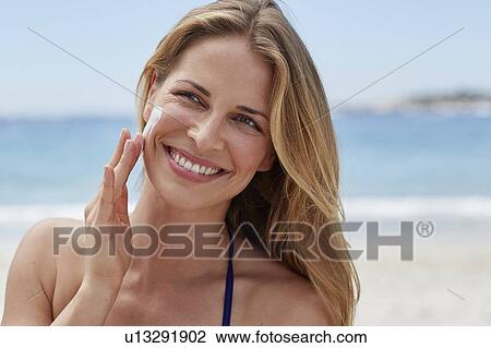 Woman applying sun cream to cheek View Large Photo Image Stock Image - Woman applying sun cream to cheek. Fotosearch