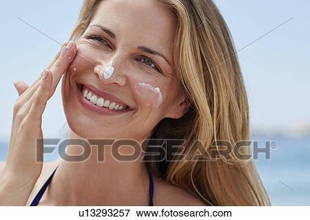 Woman applying sun cream to face View Large Photo Image Stock Photo - Woman applying sun cream to face. Fotosearch