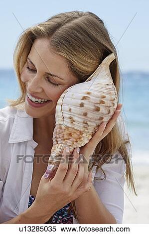 Stock Photography - Woman listening to a shell. Fotosearch