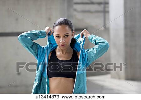 Stock Photo - Woman putting on hooded top. Fotosearch