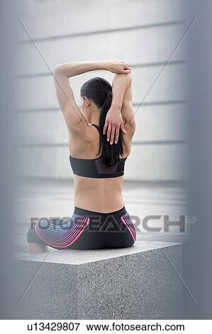 Woman sitting on wall, stretching View Large Photo Image Stock Photo - Woman sitting on wall, stretching. Fotosearch