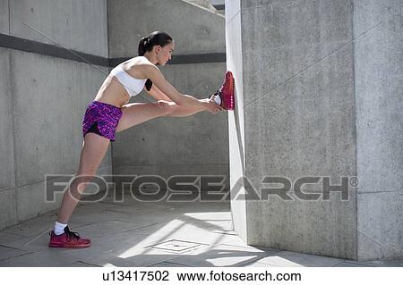 Stock Image - Woman stretching against wall. Fotosearch