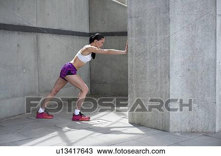 Woman stretching against wall View Large Photo Image Stock Image - Woman stretching against wall. Fotosearch