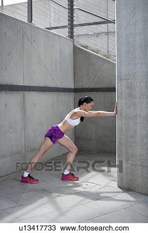 Stock Image - Woman stretching against wall. Fotosearch