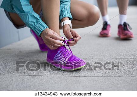 Stock Image - Woman tying laces on trainers. Fotosearch