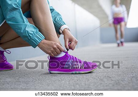 Stock Image - Woman tying laces on trainers. Fotosearch