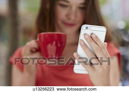 Stock Image - Woman using smartphone drinking coffee. Fotosearch