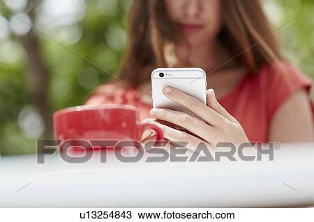 Stock Image - Woman using smartphone with coffee. Fotosearch