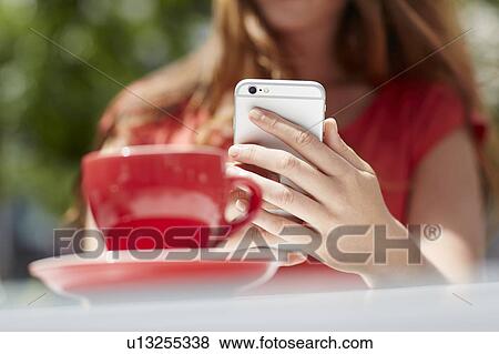 Stock Photo - Woman using smartphone with coffee. Fotosearch