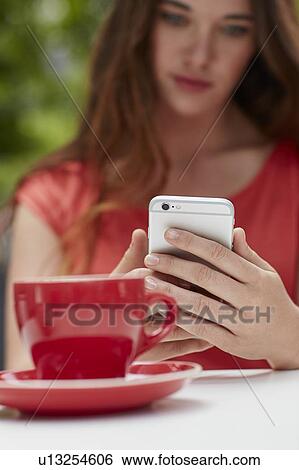 Stock Photograph - Woman using smartphone with coffee. Fotosearch