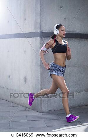Woman wearing headphones running View Large Photo Image Stock Photo - Woman wearing headphones running. Fotosearch
