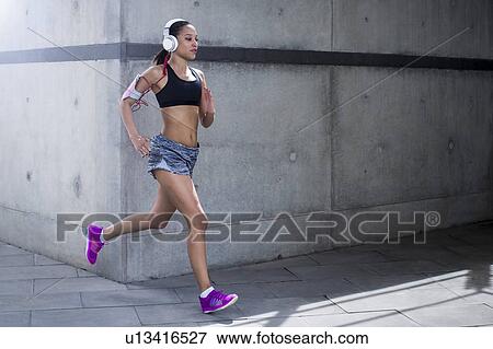 Woman wearing headphones running View Large Photo Image Stock Photo - Woman wearing headphones running. Fotosearch