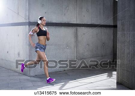 Woman wearing headphones running View Large Photo Image Stock Photography - Woman wearing headphones running. Fotosearch