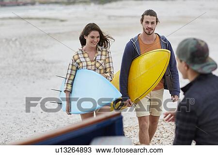Stock Image - Young couple on beach with surfboards. Fotosearch