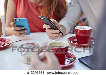 Young people in cafe using smartphones View Large Photo Image Stock Image - Young people in cafe using smartphones. Fotosearch