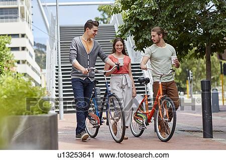 Young people walking with bikes View Large Photo Image Stock Image - Young people walking with bikes. Fotosearch
