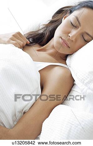 Stock Image - Young woman asleep in bed. Fotosearch