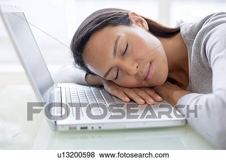 Stock Photo - Young woman asleep on laptop. Fotosearch